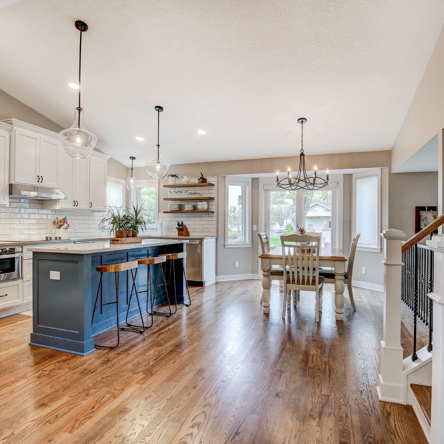 Open concept kitchen with white shaker cabinets and blue island